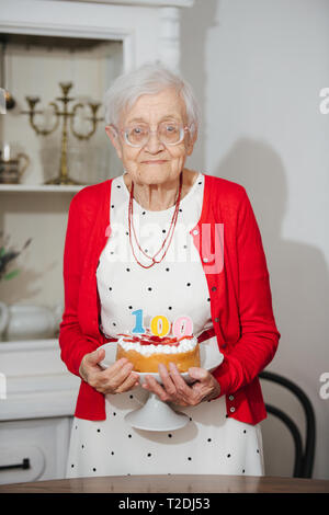 Happy Senior femme aux cheveux gris bien habillé fête son 100e anniversaire à la maison. Banque D'Images