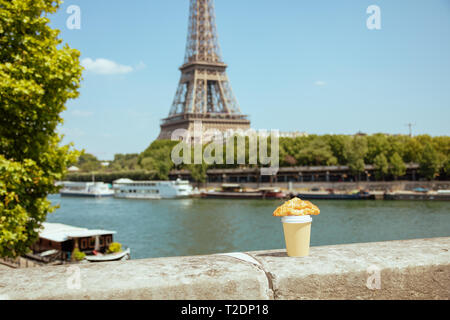 Tasse de café et un croissant sur le parapet au quai de la Seine, non loin de la tour Eiffel à Paris, France. Banque D'Images
