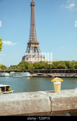 Tasse de café et un croissant sur le parapet au quai de la Seine, non loin de la tour Eiffel à Paris, France. Banque D'Images