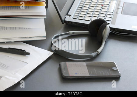 Ordinateur portable sur la table de travail avec livres, papiers, crayon, écouteurs et smartphone Banque D'Images