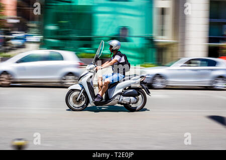 Messine, Sicile, Italie. Un homme sur un scooter (avec motion blur) sur la rue de Messine Banque D'Images