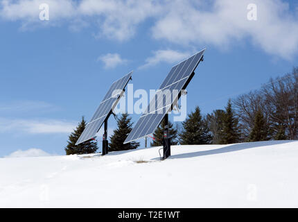 Panneaux solaires photovoltaïques résidentiels montés sur poteau sur pied libre sur une colline dans un cadre rural d'hiver. Banque D'Images