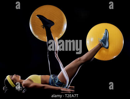 Un mixed race woman exercice exercices de fitness isolé sur fond noir avec effet lightpainting expositions multiples Banque D'Images