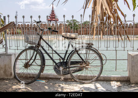 Une vieille bicyclette est de s'appuyer sur une balustrade sur une douve de l'eau avant que le Palais Royal de Mandalay, Myanmar. Banque D'Images