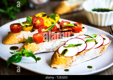 Bruschetta avec tomates cerises et radis à l'huile de basilic Banque D'Images