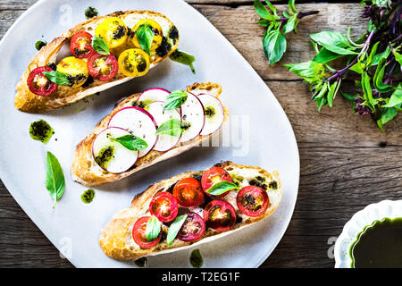 Bruschetta avec tomates cerises et radis à l'huile de basilic Banque D'Images