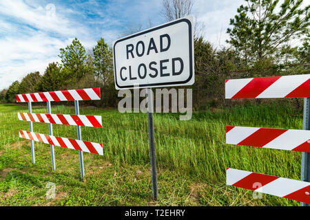 Angle horizontal de rouge et blanc à rayures avec des obstacles d'une route signe clos au milieu d'eux dans une région boisée. Banque D'Images