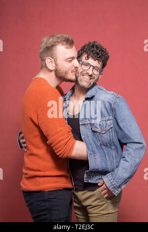 Couple gay, serrant et ensemble tout en étant heureux, souriant tandis qu'à la recherche d'appareil photo. Banque D'Images