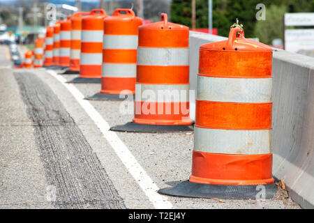 Gros plan horizontal de l'orange et blanc à rayures de barils de la circulation en bas du côté d'une route avec une faible profondeur de champ. Banque D'Images
