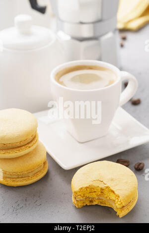 Macarons français jaune avec remplissage des fruits et une tasse d'espresso. Coffee Time. Banque D'Images