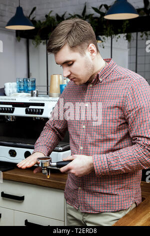 Beau jeune hipster barista faire le café pour ses clients dans le café. Banque D'Images