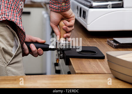 Beau jeune hipster barista faire le café pour ses clients dans le café. Banque D'Images