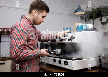 Beau jeune hipster barista faire le café pour ses clients dans le café. Banque D'Images