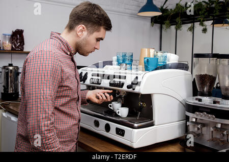 Beau jeune hipster barista faire le café pour ses clients dans le café. Banque D'Images