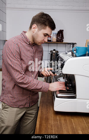 Beau jeune hipster barista faire le café pour ses clients dans le café. Banque D'Images