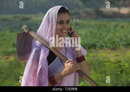 Portrait of a smiling woman carrying un chat sur son épaule dans un champ agricole de conversations au téléphone mobile. Banque D'Images