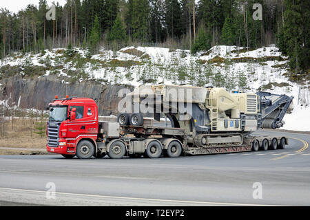 Forssa, Finlande - le 30 mars 2019 : Scania R620 camion d'Makitalo Veljekset Oy avec Metso Lokotrack sur remorque broyeur tourne à droite à l'intersection de la route. Banque D'Images