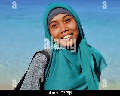 Jeune femme musulmane indonésienne porte un hijab bleu accessoirisée avec un hijab broche et pose pour la caméra. Banque D'Images