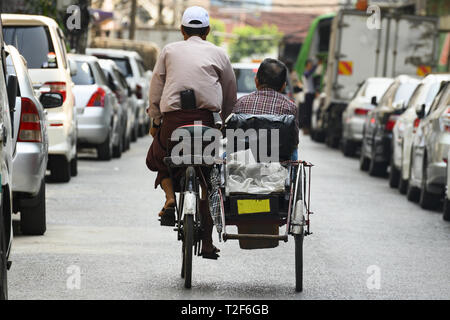 Un conducteur non identifié de Kaa Sai est le transport d'un passager sur son side car parmi les rues étroites de Yangon, Myanmar. Banque D'Images