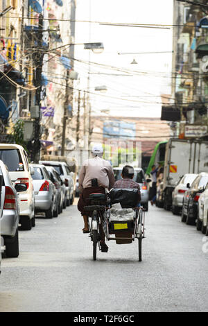 Un conducteur non identifié de Kaa Sai est le transport d'un passager sur son side car parmi les rues étroites de Yangon, Myanmar. Banque D'Images