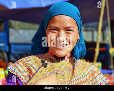 Jeunes vietnamiens des H'Mong femme wearsa fleurs colorés traditionnels vêtements H'Mong et un foulard bleu et sourit pour la photo. Banque D'Images