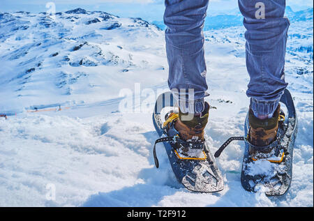 Gros plan de l'homme aux jambes en raquettes, debout sur le bord de la pente enneigée de Krippenstein mont avec une vue sur les Alpes Dachstein sur le contexte, Sal Banque D'Images