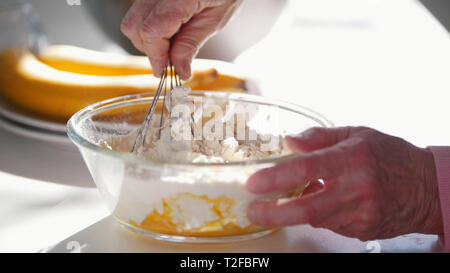 Faire des crêpes. Une vieille femme mélange les ingrédients. Milieu shot Banque D'Images