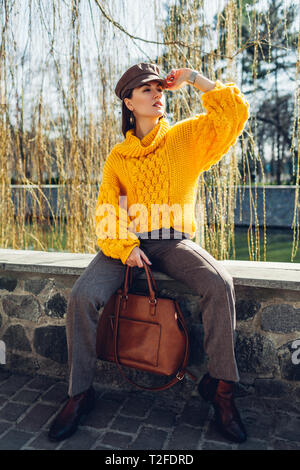 Jeune femme portant tenue et élégant sac à main de portefeuille à l'extérieur. Femme printemps Vêtements et accessoires. Mode de rue Banque D'Images