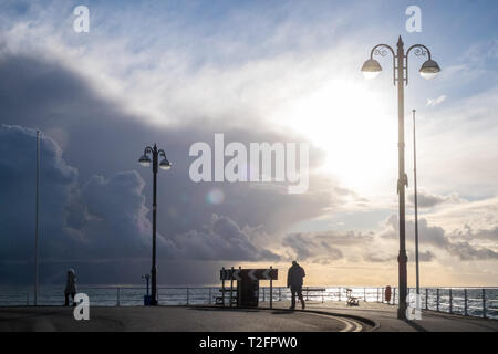 Aberystwyth, Ceredigion, pays de Galles. 2ème apr 2019. Météo France : Le soleil commence à définir à Aberystwyth, Ceredigion, pays de Galles, Royaume-Uni personnes le long de la promenade à la fin d'un jour nuageux et ensoleillé. Crédit : Paul Quayle/Alamy Live News Banque D'Images