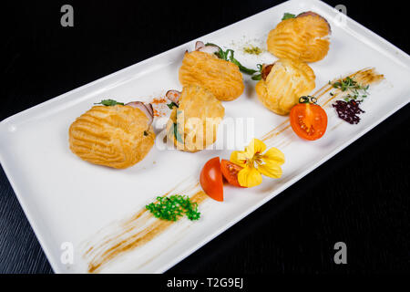 Mousse au fromage avec du bacon dans eclair, servi sur une assiette et couverts de vert et de tomate cherry Banque D'Images