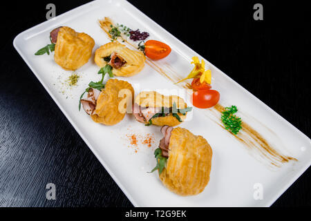 Mousse au fromage avec du bacon dans eclair, servi sur une assiette et couverts de vert et de tomate cherry Banque D'Images