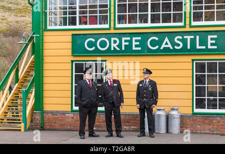 Station Masters debout sur la plate-forme à l'extérieur de la boîte de signalisation de Swanage Railway train à vapeur vintage à Corfe Castle, Dorset UK en mars Banque D'Images