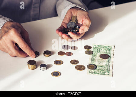 Dollar et pièces en old woman's hands on white background with copy space Banque D'Images