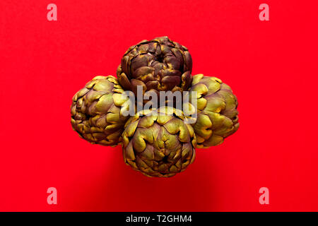 Groupe de 4 Artichauts isolées de ci-dessus sur un fond rouge concept flatlay Banque D'Images