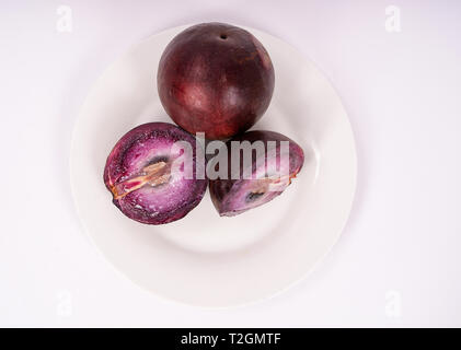 Deux fruits caimito sur une plaque, l'un d'eux coupe en deux Banque D'Images