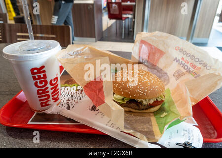 Un repas whopper acheté à un fast-food Burger King. Un whopper burger et une tasse de soda sont vus sur un plateau sur une table. Banque D'Images