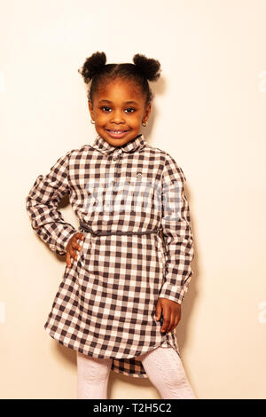 Portrait pleine hauteur de Little Black girl smiling over wall et portant des vêtements à carreaux Banque D'Images