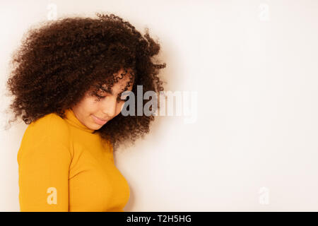 Belle jeune femme aux cheveux bouclés à la timide vers le bas près de la tête et des épaules portrait Banque D'Images