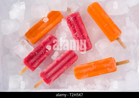 Sucettes glacées aux fraises et orange sur la glace. Vue d'en haut. Banque D'Images