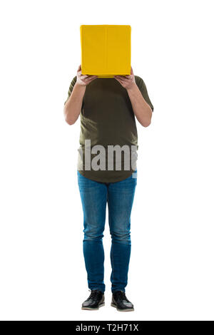 Full Length portrait of young man holding incognito occasionnels une boîte jaune au lieu de tête blanc. Se cacher derrière les visages des gens introverti masque. S Banque D'Images