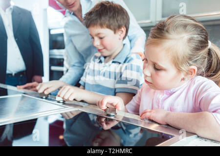 Les enfants de la nouvelle cuisine leurs parents sont sur le point d'acheter des boutons de numérotation du four Banque D'Images