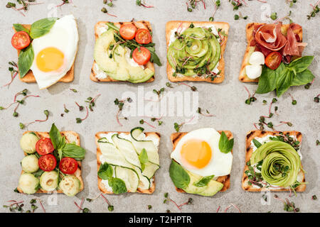 Vue de dessus de toasts avec des légumes, œufs frits et de prosciutto sur la surface texturée Banque D'Images