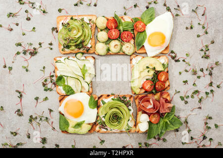 Vue de dessus de toasts avec des légumes, œufs frits et de prosciutto sur la surface texturée Banque D'Images