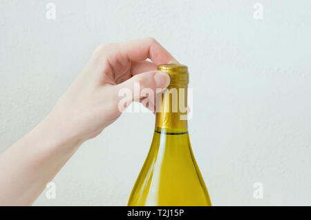 Part caucasian girl ouvre une bouteille de vin. Close-up. Arrière-plan blanc. Banque D'Images