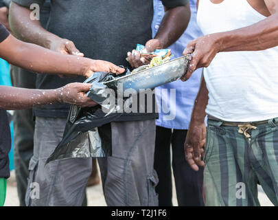 Mettre pêcheur le poisson frais sur un sac à la vente du marché de poissons local dans la région de Galle, au Sri Lanka. Banque D'Images