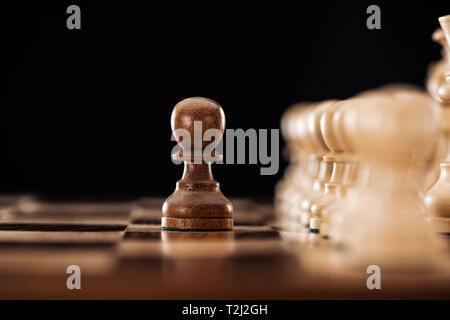 Focus sélectif d'échiquier en bois avec pièces d'échecs et pion devant isolated on black Banque D'Images