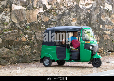 Galle, Sri Lanka - Février 18th, 2019 : Un tuk tuk chauffeur en attente pour les passagers stationné à Matara Road à Galle, au Sri Lanka. Banque D'Images