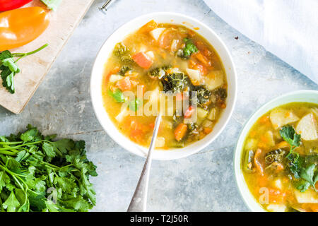 Minestrone, sur la Cuvette et pot de légumes couper sur une cutboard tomate cerise, citron vert, brun sur un fond blanc en béton Banque D'Images