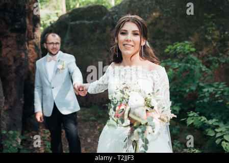 Mariée et le marié sur jour de mariage, s'étreindre, près d'un rocher ou une grosse pierre. Banque D'Images