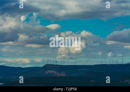 Quelques tours de moulins à vent sur les montagnes sous un ciel couvert avec des nuages blancs Banque D'Images